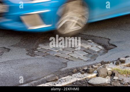 Leipzig, Deutschland. Februar 2021, 19th. Ein Auto fährt über eine Straße mit Schlaglöchern. Wie in jedem Winter sind die Straßen besonders durch den Wechsel von Frost und Tauwetter betroffen. Quelle: Jan Woitas/dpa-Zentralbild/ZB/dpa/Alamy Live News Stockfoto