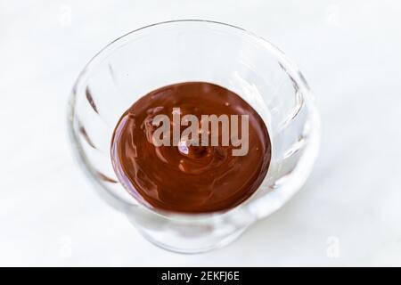Nahaufnahme von roher Flüssigkeit cremig glatte heiße geschmolzene Schokolade Kakao Mousse Sahne Icing Sirup Sauce in kleinen Glasschüssel Schüssel Stockfoto