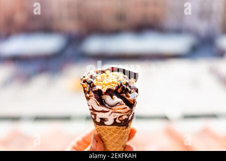 Hand hält eine weiße Vanille Schokolade Eis Gelato Kegel mit Hintergrund von Warschau, Polen alten Marktplatz historischen Gebäuden in der Stadt Stockfoto