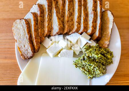 Holztisch Hintergrund mit flacher Oberseite Nahaufnahme Blick auf gesunde Vegan vegetarisch Mittag-oder Abendessen grünen Gemüse Pesto Käse Scheiben Würfel und geräucherter Ba Stockfoto