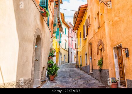 Chiusi, Italien schmale Gasse in kleinen historischen mittelalterlichen Dorf in der Toskana während sonnigen Tag mit orange gelb bunten bunten Wänden ein Stockfoto