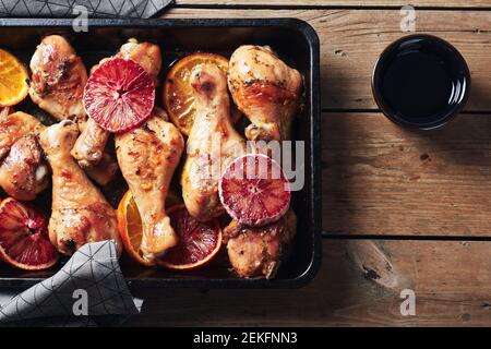 Würzen Sie gebratene Hähnchendrumstick in der Bratpfanne. Gebackene Hähnchenschenkel mit Orangen. Stockfoto