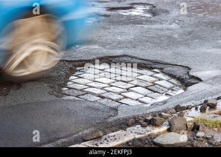 Leipzig, Deutschland. Februar 2021, 19th. Ein Auto fährt über eine Straße mit Schlaglöchern. Wie in jedem Winter sind die Straßen besonders durch den Wechsel von Frost und Tauwetter betroffen. Quelle: Jan Woitas/dpa-Zentralbild/ZB/dpa/Alamy Live News Stockfoto