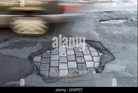 Leipzig, Deutschland. Februar 2021, 19th. Ein Auto fährt über eine Straße mit Schlaglöchern. Wie in jedem Winter sind die Straßen besonders durch den Wechsel von Frost und Tauwetter betroffen. Quelle: Jan Woitas/dpa-Zentralbild/ZB/dpa/Alamy Live News Stockfoto