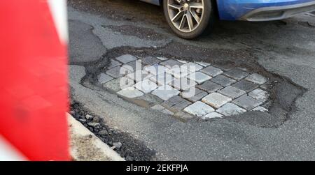 Leipzig, Deutschland. Februar 2021, 19th. Ein Auto fährt über eine Straße mit Schlaglöchern. Wie in jedem Winter sind die Straßen besonders durch den Wechsel von Frost und Tauwetter betroffen. Quelle: Jan Woitas/dpa-Zentralbild/ZB/dpa/Alamy Live News Stockfoto