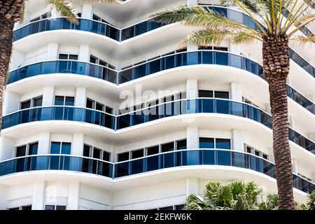 Abstrakter Blick auf Wohnkomplex mit vielen Fenstern, Balkonen in Weißblau an sonnigen Tagen mit Palmen Stockfoto