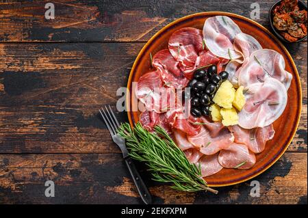 Italienische Fleischplatte mit Prosciutto-Schinken, bresaola, Pancetta, Salami und Parmesan. Dunkler Holzhintergrund. Draufsicht. Speicherplatz kopieren Stockfoto
