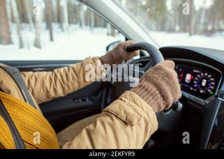 Handschuhen von jungen modernen aktiven Mann in warmer Winterkleidung Halten durch Steuern, während Sie im Auto sitzen und fahren während Reisen Stockfoto