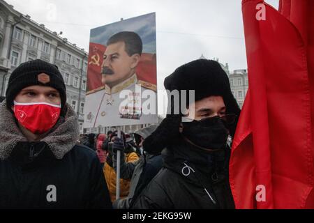 Moskau, Russland. Am 23rd. Februar gehen 2021 Anhänger der kommunistischen Partei mit roten Fahnen und einem Porträt Josef Stalins zu einer Kranzniederlegung am Grab des unbekannten Soldaten, nahe der Mauer des Kremls, während der nationalen Feierlichkeiten zum Tag des "Verteidigers des Vaterlandes" in Moskau, Russland Stockfoto