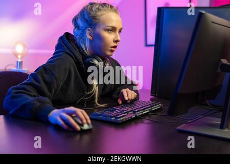 Fokussierte professionelle E-Sport-Gamer Mädchen in Hoody Online-Video spielen Spiel auf dem PC Stockfoto
