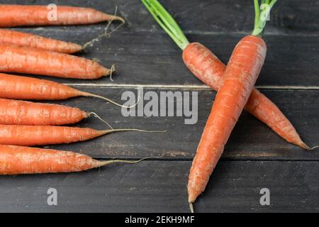 Ein Bündel Karotten mit zwei gekreuzten frischen Karotten auf Holz Background.Creative gesunde Lebensmittel Lebensstil, rohes Gemüse Vorlage Konzept Stockfoto