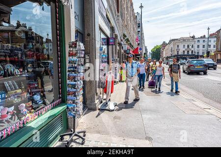 London, Großbritannien - 24. Juni 2018: Souvenirladen mit Menschen zu Fuß auf Bürgersteig Straße durch viele Souvenirs im Sommer in Großbritannien Stockfoto
