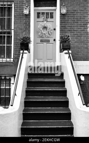 Hellgetönte Eingangstür auf Backstein in Brooklyn, New York, NYC, USA. Lackierte Stufen führen bis zur Eingangstür an dieser Fassade des Wohngebäudes. Stockfoto
