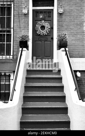 Dunkelgetönte Eingangstür auf Backstein in Brooklyn, New York, NYC, USA. Lackierte Stufen führen bis zur Eingangstür an dieser Fassade des Wohngebäudes. Stockfoto