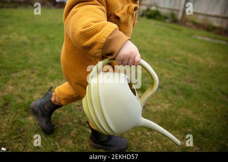 Ein kleines Kind hilft im Garten Pflanzen wässern Mit einer Gießkanne Stockfoto