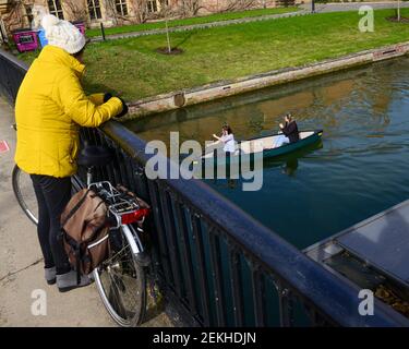 Cambridge, UK, 20-02-21, zwei junge Erwachsene Kanu entlang der Fluss CAM in cambridge , ein Radfahrer hält und beobachtet sie ihren Weg Stockfoto