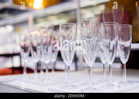 Reihen von glänzenden leeren hohen Gläsern mit Reflexen im Restaurant. Catering-Konzept.Set von leeren Weingläser in Reihen angezeigt. Vorbereitung für Stockfoto