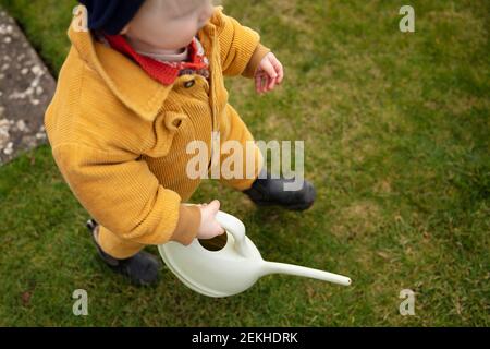 Ein kleines Kind hilft im Garten Pflanzen wässern Mit einer Gießkanne Stockfoto