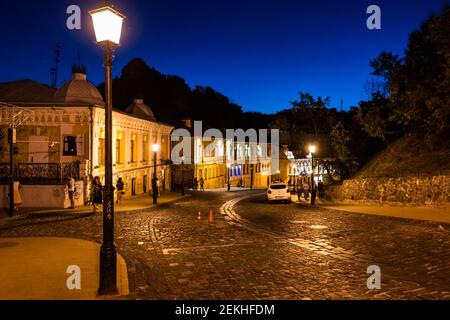 Kiew, Ukraine - 10. August 2018: Andriyivskyy Uzviz Abstieg mit Menschen draußen auf Kopfsteinpflaster Straße in der Nacht beleuchtete Laterne Stockfoto