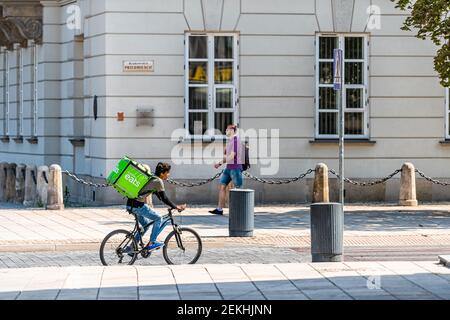 Warschau, Polen - 23. August 2018: Uber isst Fahrradmann Person mit grünem Schild in der Altstadt historische Straße in der Hauptstadt während sonnigen Sommertag Stockfoto