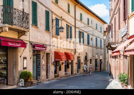 Montalcino, Italien - 26. August 2018: Dorf mit Menschen in der Toskana während des Sommertages mit engen Gassen und bunten Steinmauern Zeichen für Gelater Stockfoto