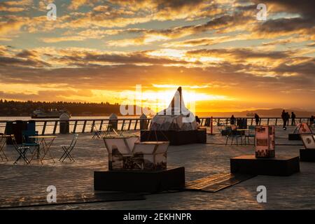 WA19340-00...WASHINGTON - Abend am Pier 62, wo sich die Menschen versammeln, während die Sonnenuntergänge über der Elliot Bay in Seattle. Stockfoto