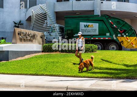 Sunny Isles Beach, USA - 8. Mai 2018: Trump Towers Condominium Apartment Komplex Gebäude in Miami, Florida mit Frau, die Hund auf grünem Gras zu Fuß Stockfoto