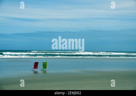 Eine grüne und rote Strandliege vor dem Meer am Strand Stockfoto