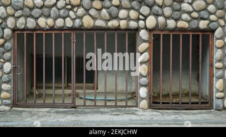 Kieselsteinwand mit altem rostigen Keller Sicherheitsfenster Stockfoto