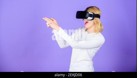 Fesselnde Interaktion Virtual Reality. Frau Kopf montiert Display violetten Hintergrund. Virtual Reality-Drehgalerie. Mädchen verwenden moderne Technologie vr Headset spielen Shooter-Spiel. Dame mit Pistole Geste. Stockfoto