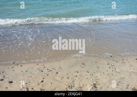 Weiche Welle mit weißem Schaum, Meeresbrandung am Sandstrand. Reisekonzept, Urlaub am Meer. Stockfoto