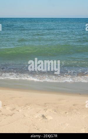 Meeresküste mit sanfter Welle am Sandstrand. Natürlicher Hintergrund für Sommerferien. Stockfoto