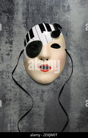 Porzellanmaske einer weiblichen Muse mit Tastatur und Hinweis auf einer Steinfliese Stockfoto