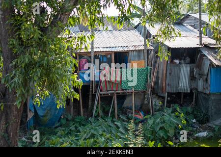 Ein einfaches Haus aus konjugiertem Eisen, das auf ein paar Holzpfosten über einem Fluss außerhalb von Yangon, Myanmar, steht Stockfoto