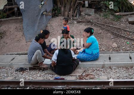 YANGON, MYANMAR - DEZEMBER 31 2019: Fünf burmesische Frauen spielen ein Spiel an den Bahngleisen außerhalb Yangons, ein Kind kommt vorbei Stockfoto