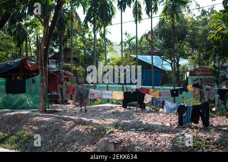 YANGON, MYANMAR - DECEMEBER 31 2019: Wäsche hängt in der Sonne in einem burmesischen Dorf mit großen Palmen Stockfoto