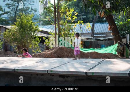 YANGON, MYANMAR - DEZEMBER 31 2019: Zwei junge burmesische Kinder spielen zusammen an einem Bahnhof außerhalb von Yangon Stockfoto