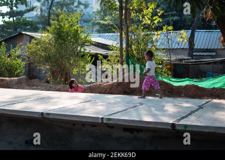 YANGON, MYANMAR - DEZEMBER 31 2019: Zwei junge burmesische Kinder spielen zusammen an einem Bahnhof außerhalb von Yangon Stockfoto