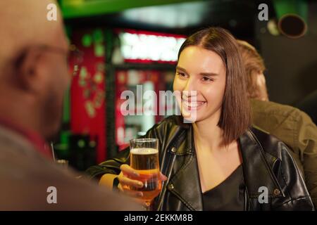 Glückliche junge Frau, die sich mit ihrer Freundin in der Kneipe trifft Gemeinsam Bier trinken und reden Stockfoto