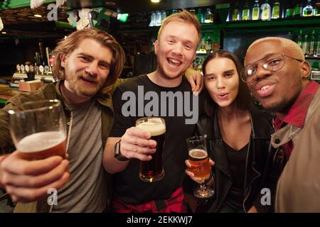 Porträt glücklicher junger Menschen, die Bier trinken und lächeln Kamera im Pub Stockfoto