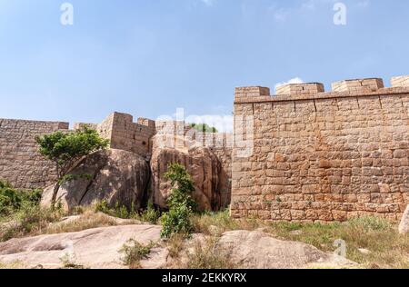 Chitradurga, Karnataka, Indien - 10. November 2013: Fort oder Elusuttina Kote. Braune Steinmauer mit riesigen Felsbrocken unter blauem Himmel. Einige Stockfoto