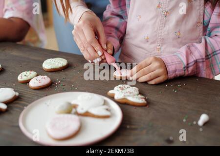 Nahaufnahme der Mutter Dekoration hausgemachte Kekse zusammen mit ihrer Tochter Am Tisch Stockfoto