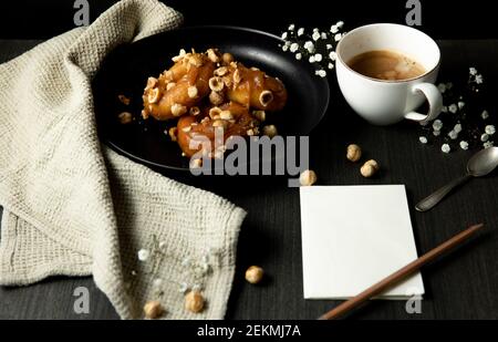 Donuts mit Karamell und Haselnüssen, Tasse Kaffee auf dem rustikalen Tisch Stockfoto