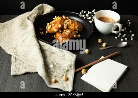 Donuts mit Karamell und Haselnüssen, Tasse Kaffee auf dem rustikalen Tisch Stockfoto