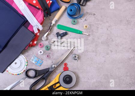 Nähartikel und Zubehör für Handarbeiten, Stoff, Faden, Schere, Verschluss, Schneideplotter, Maßband, auf grauem Hintergrund Stockfoto