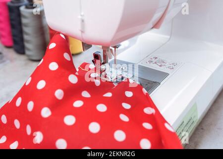 Weiße Nähmaschine mit rotem Stoff in Hausschneiderwerkstatt Stockfoto