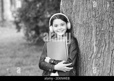 Mädchen hören Audio tragen Lehrbücher entspannend Park Hintergrund, Sound in ihrem Kopf Konzept. Stockfoto