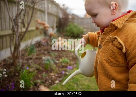 Ein kleines Kind hilft im Garten Pflanzen wässern Mit einer Gießkanne Stockfoto