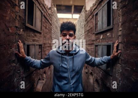Portrait von fokussierten motivierten afro-amerikanischen jungen attraktiven athletischen Mann mit Ohrhörer, die in der Mitte des verlassenen Ortes stehen Von zwei w Stockfoto