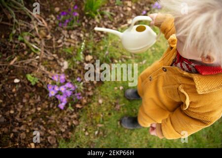 Ein kleines Kind hilft im Garten Pflanzen wässern Mit einer Gießkanne Stockfoto